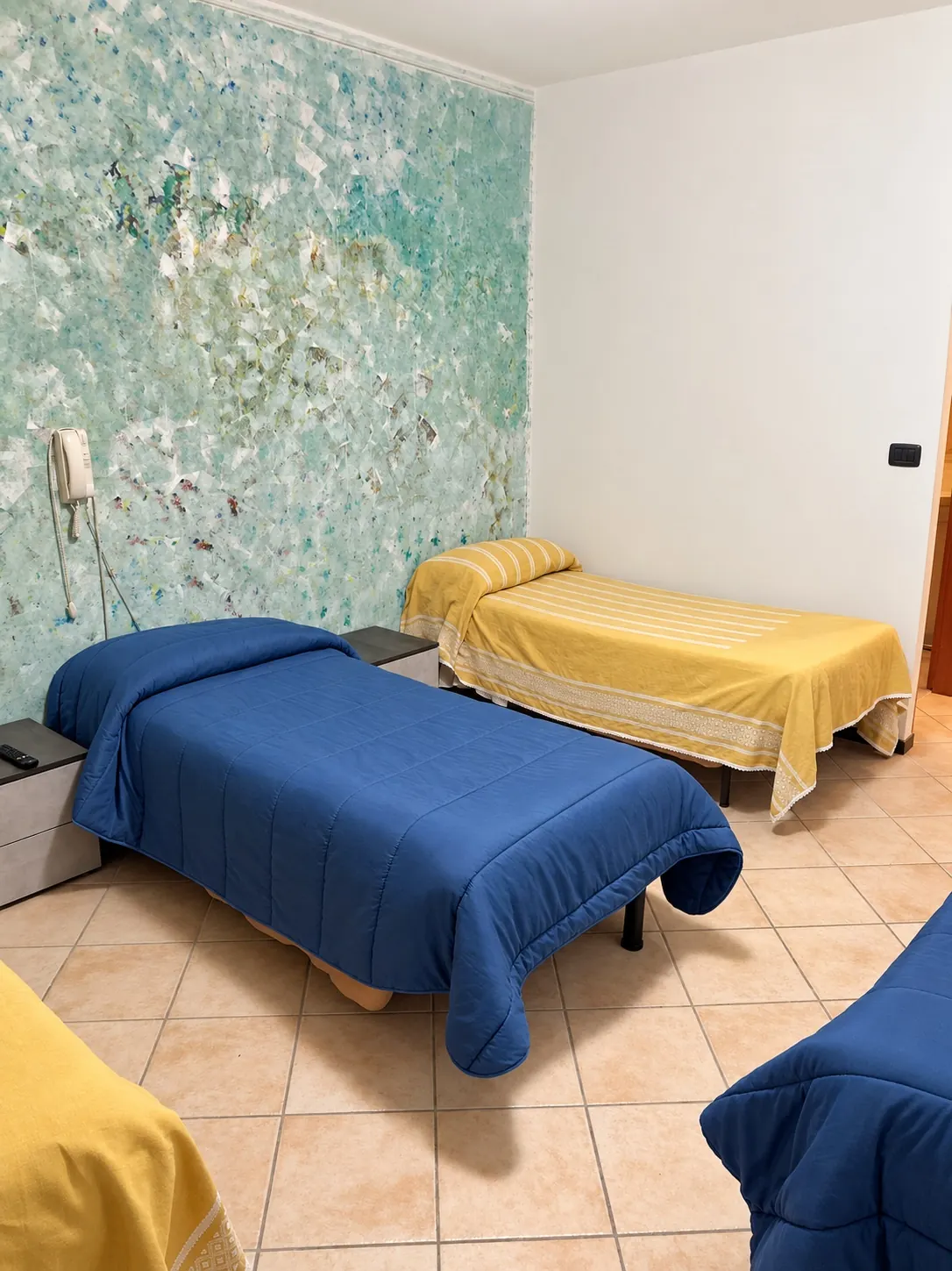 Camera coi letti singoli blu e gialli e la parete decorata