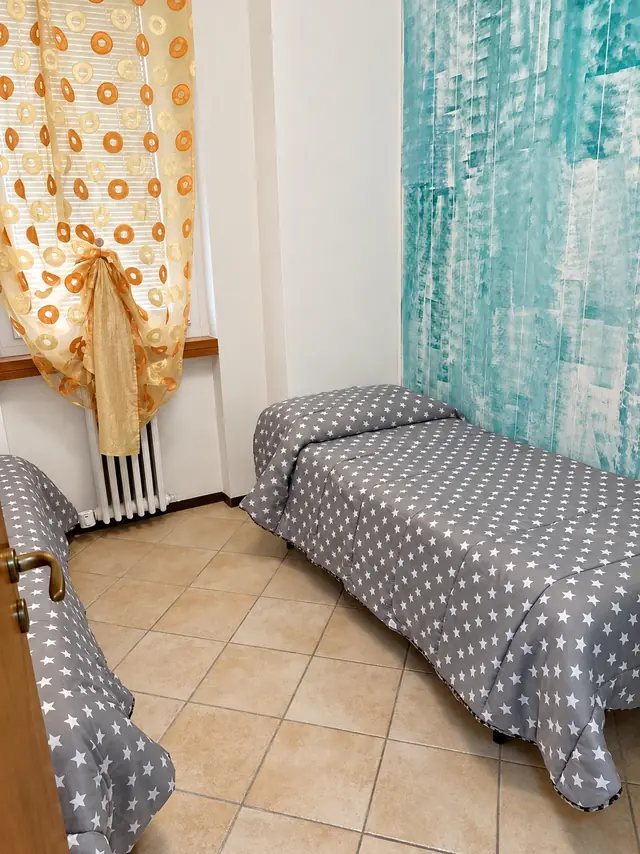 Camera con i letti singoli a pois e la tenda arancio