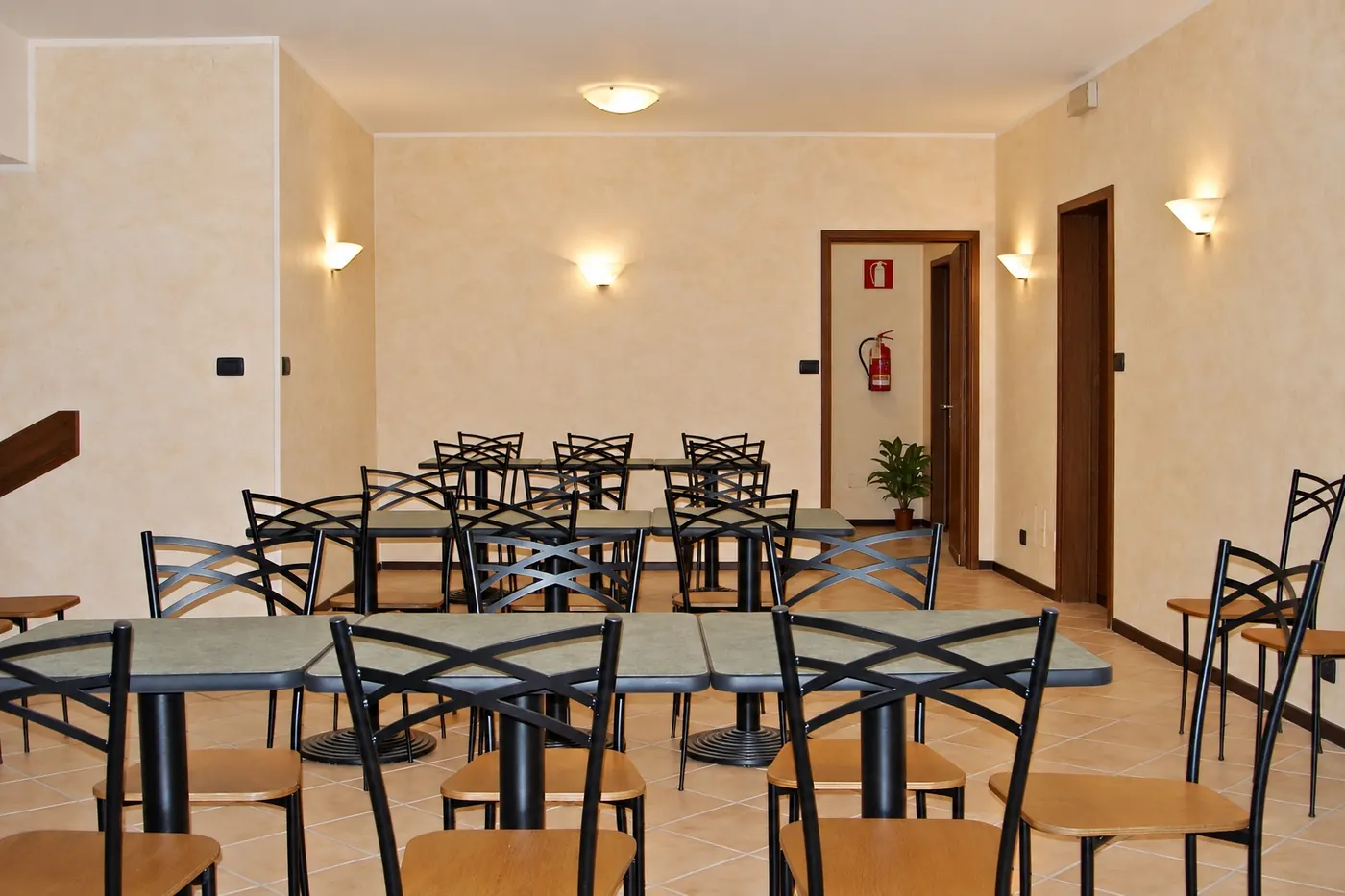 La sala con i tavoli e le sedie scure, le luci a muro