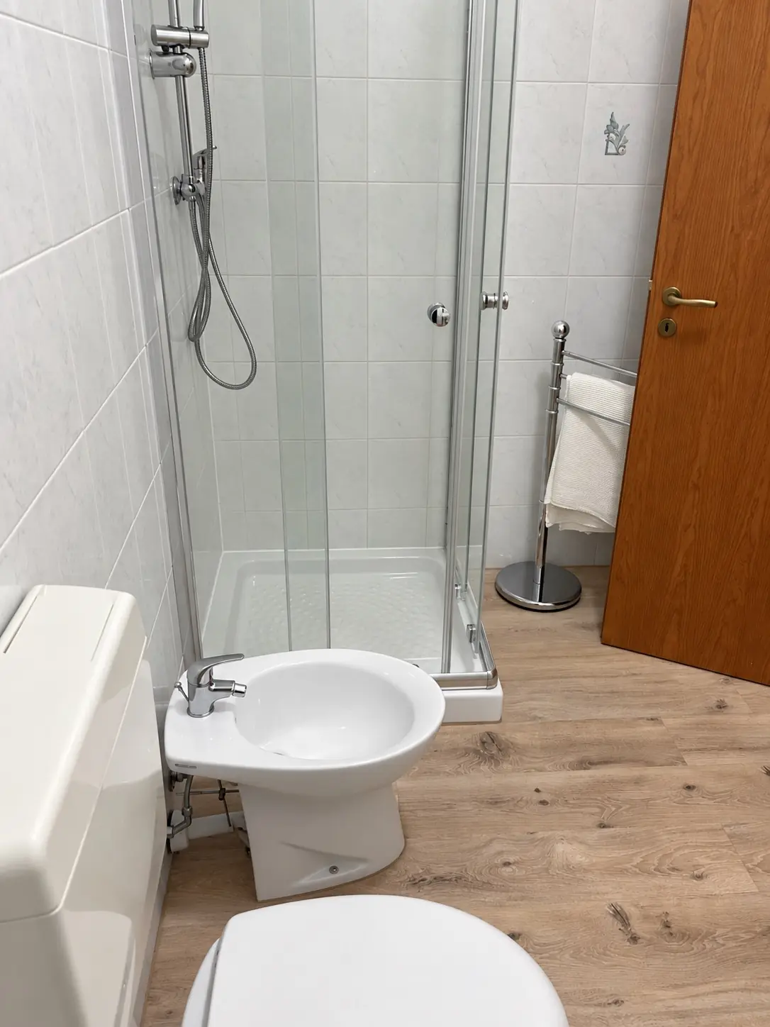 Bagno con la doccia in vetro, i sanitari e il pavimento effetto legno