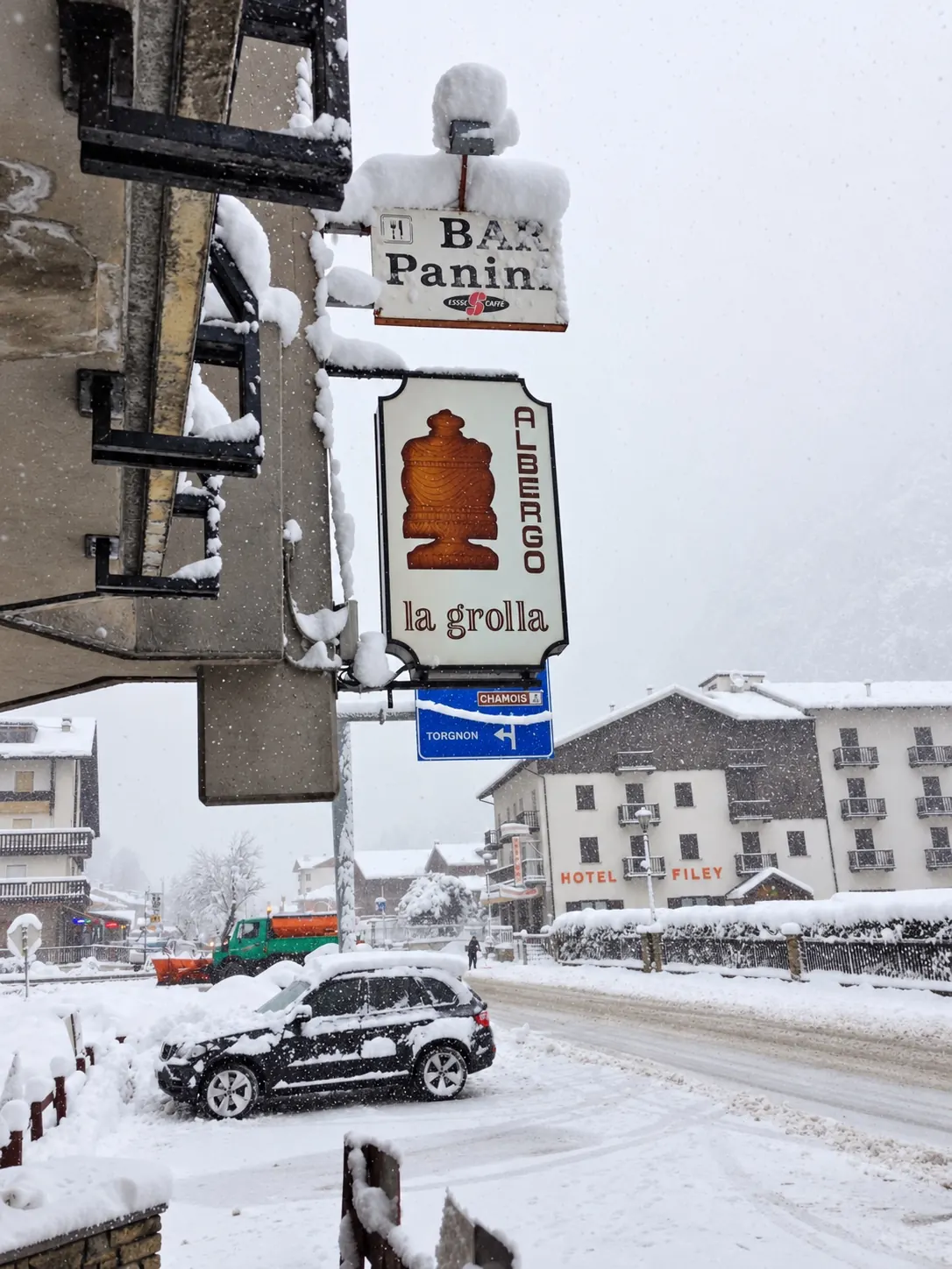 Das Schild des Albergo La Grolla mit der gezeichneten Grolla, im Schneefall an der Straße von Filey